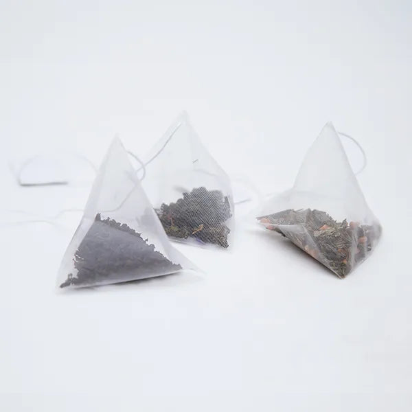 Clear pyramid tea bag filled with mountain green tea – suitable for espresso-style brewing.