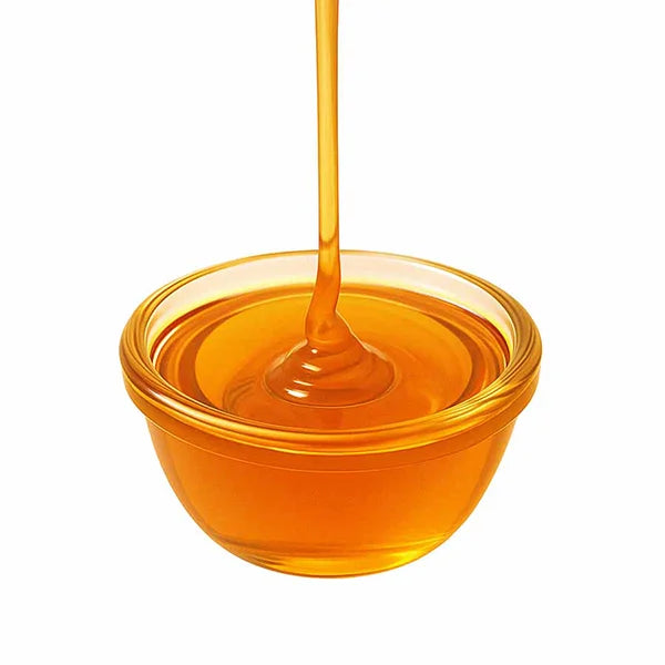 Amber raw sugar syrup drizzling into a glass bowl – showcasing thick, smooth texture.