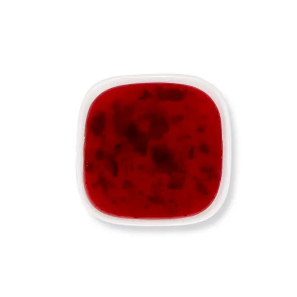 Top view of strawberry syrup with visible fruit bits and vibrant red hue.