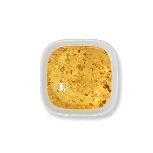 Top view of osmanthus syrup with visible flower petals and golden clarity.