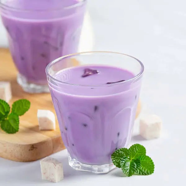 Taro milk drink in soft purple hue with ice and taro cubes.
