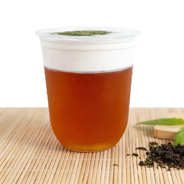 Ruby red black tea drink topped with milk foam, featuring layered color and rich texture.
