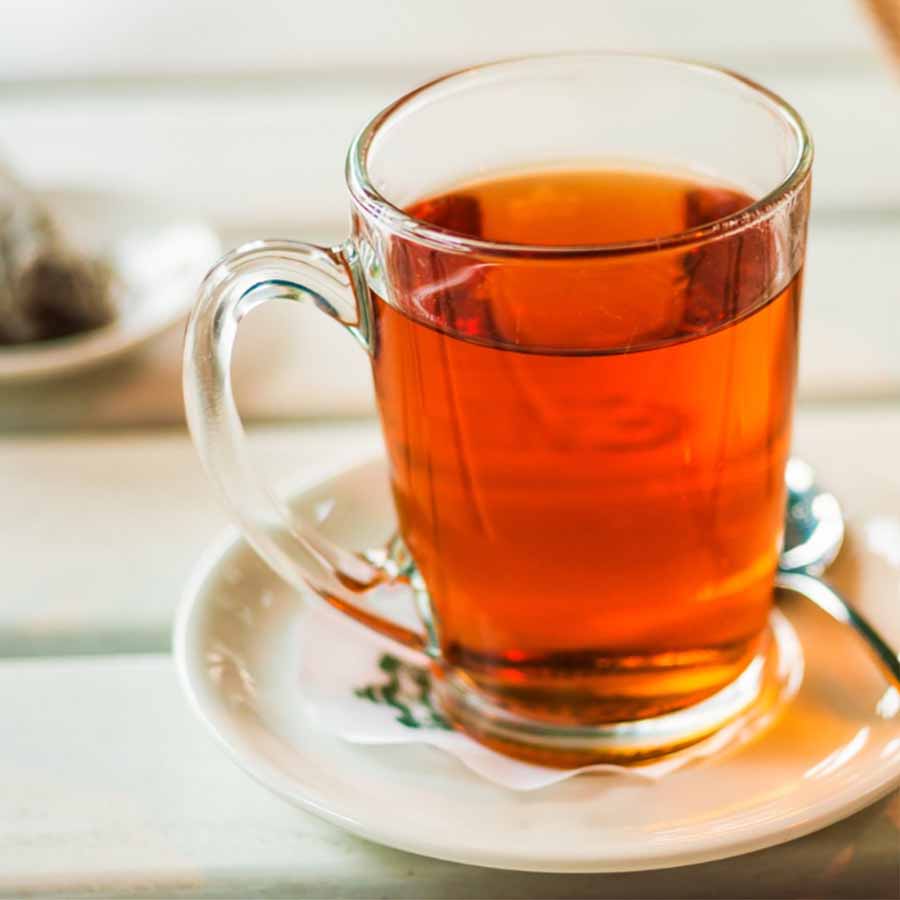 Final brewed red pu erh tea served in a clear glass mug.